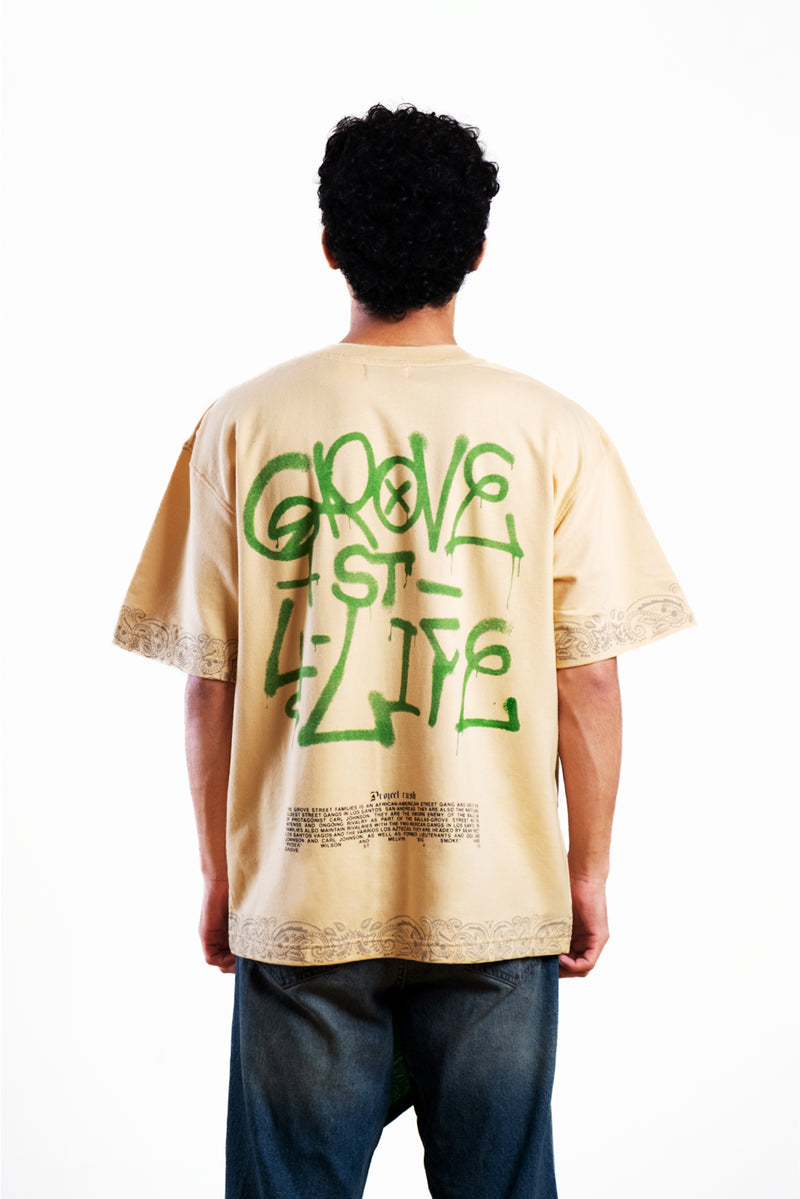 Person wearing a beige t-shirt with green text on the back, standing against a white background