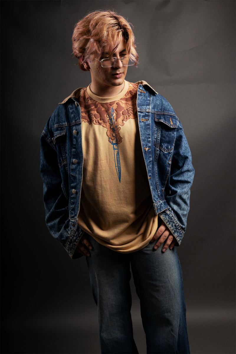 Person wearing a denim jacket and beige shirt with graphic design on a dark background